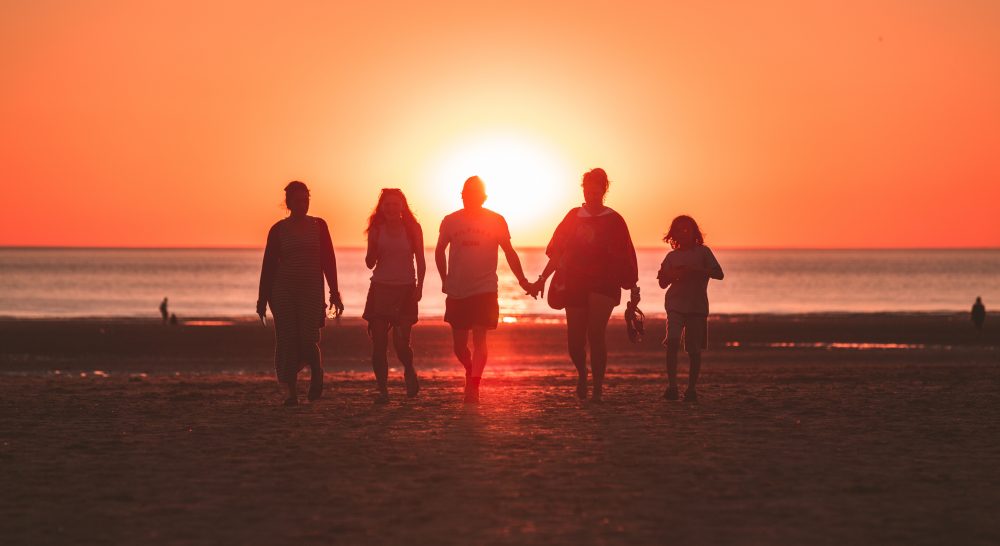 silhouette of family walking back from the water on the beach