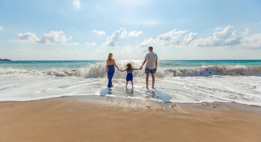 family holding hands on the beach near the ocean