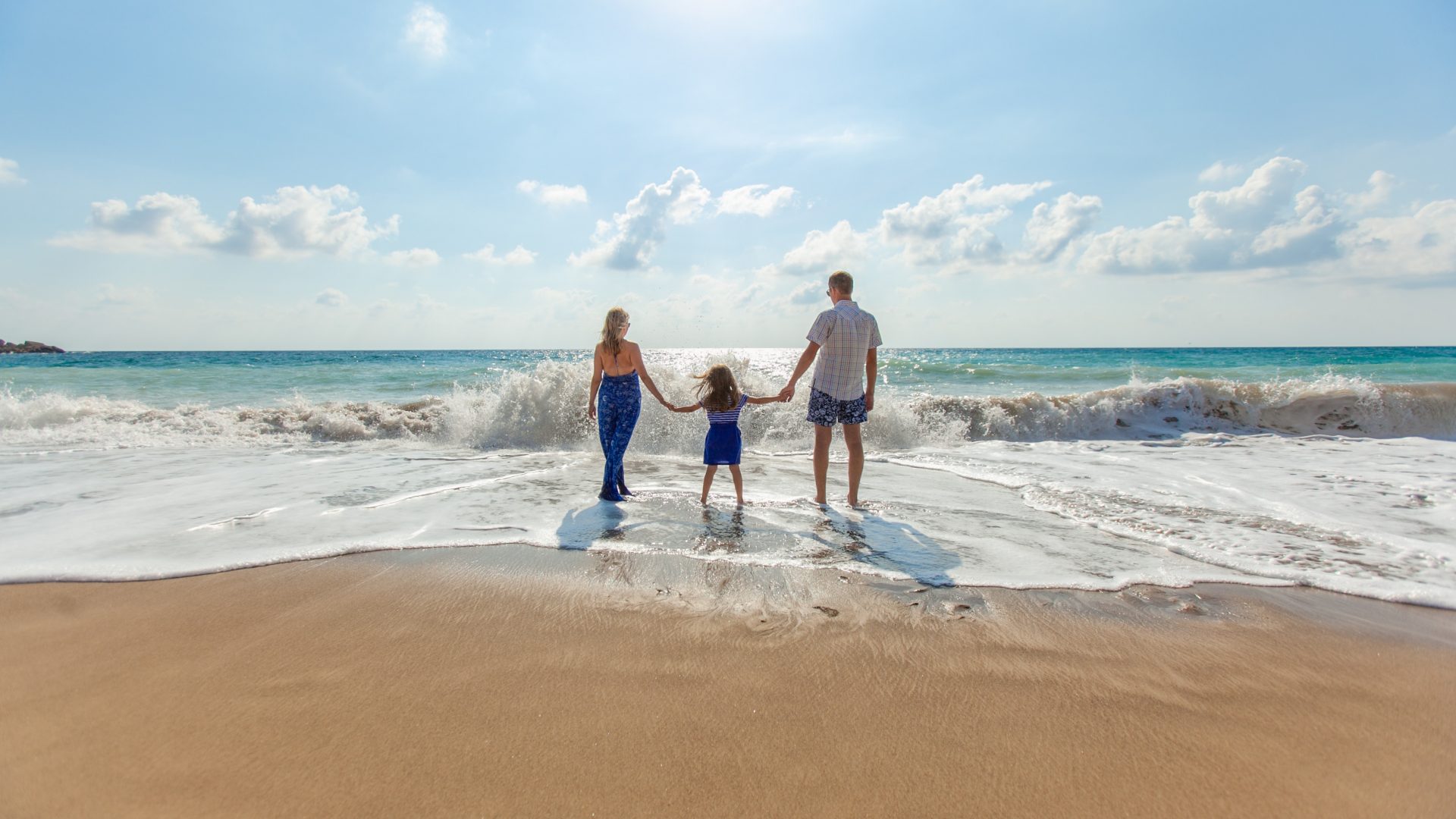 family holding hands on the beach near the ocean