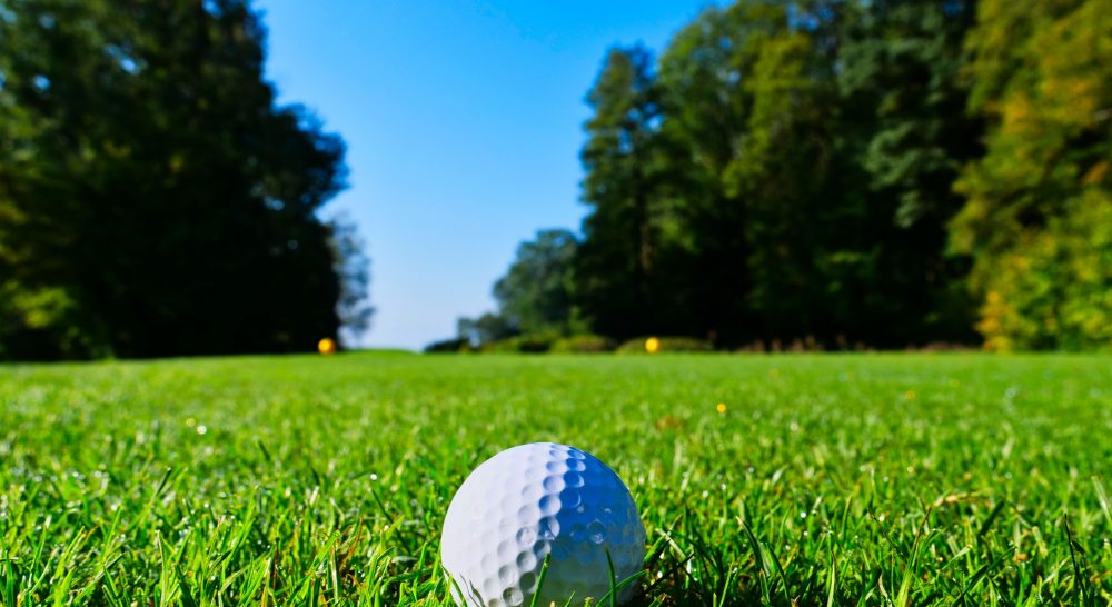 A lush green golf course and ball, which is what you want for golf weekends away in the Algarve!